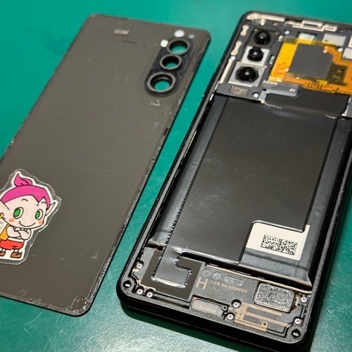 Xperia 5 IIの背面パネルをヒートガンで温めて慎重に取り外し、分解作業を開始している様子。